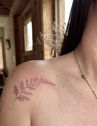 delicate handpoked fern tattoo on womens shoulder flowing towards the collar bone