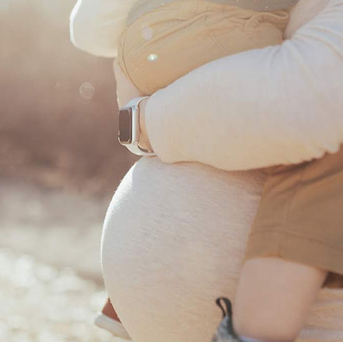 mother holding toddler on her pregnant stomach represening prenatal physical therapy