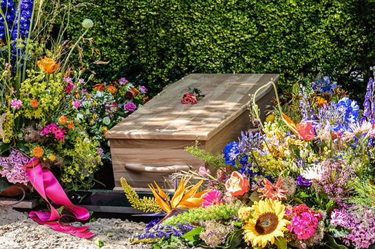 People loss and mourning concept, a wooden coffin with beautiful flowers arrangement befo