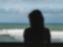 Silhoutte of a young woman facing away from viewer, looking out at the ocean