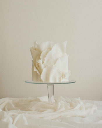 Single-tier bespoke wedding cake with hand-torn ruffles and mini sugar roses by Copper Rose, designed for an intimate wedding in Kenmore by Loch Tay, Scotland.