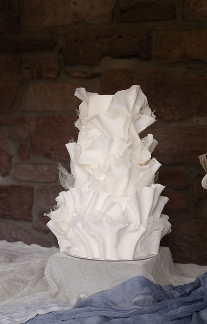 A contemporary wedding cake featuring intricate, hand-sculpted ruffles by Copper Rose, inspired by the movement of the Scottish landscape.
