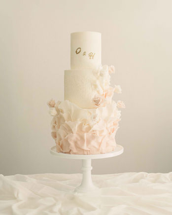 Three-tier bespoke wedding cake with hand-torn ruffles and soft peach sugar petals by Copper Rose, Scotland.