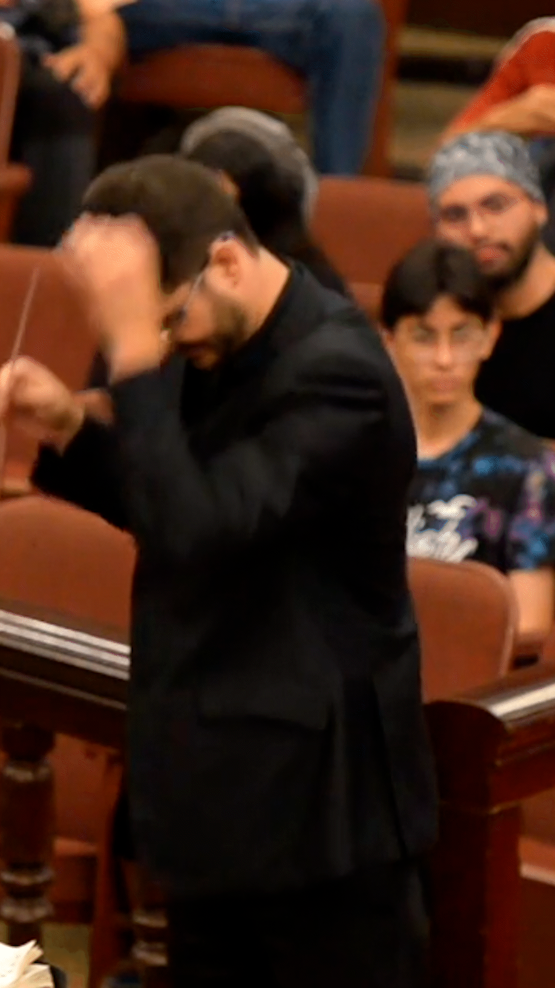 Conductor Camilo Téllez passionately leads an orchestra, showcasing expressive gestures and dynamic 