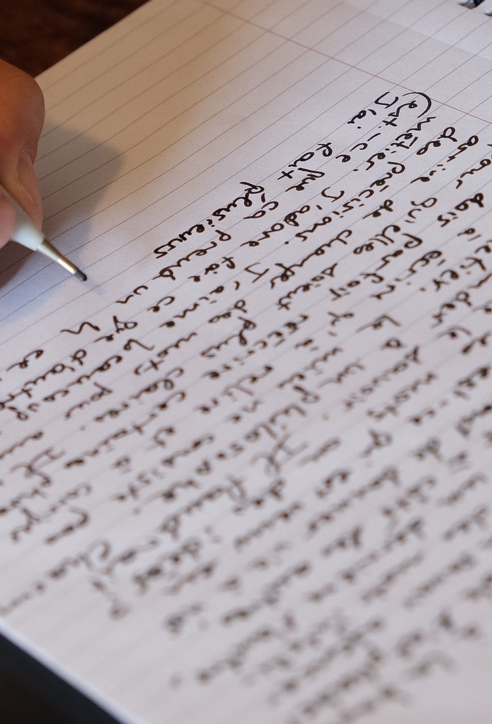 main rédigeant un texte à la main dans un cahier ligné