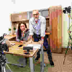 man and woman Kamla-Kay at office desk with camera equipment