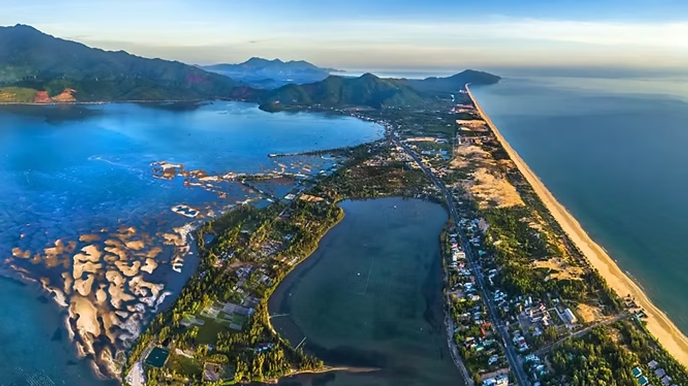 Lang Co Bay in Hue at sunrise with golden light, calm sea, and scenic mountains