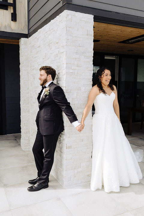 bride and groom opt for a first touch instead of a first look, reaching for one another's hands around a corner