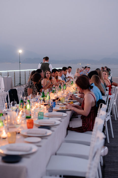 wedding guests enjoy a candlelit dinner on the dock with colorful glasses