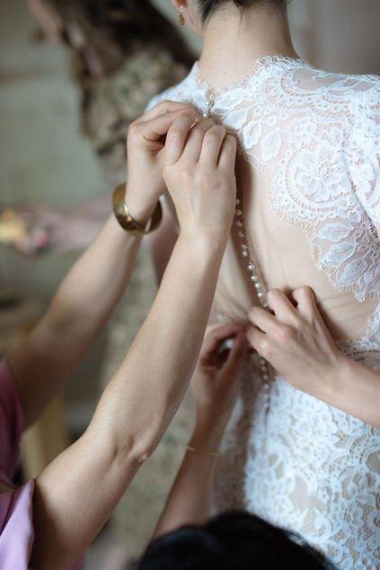 bridesmaids help bride into her dress
