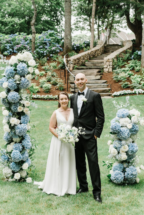 the bride and groom pose by their lush luxury ceremony florals
