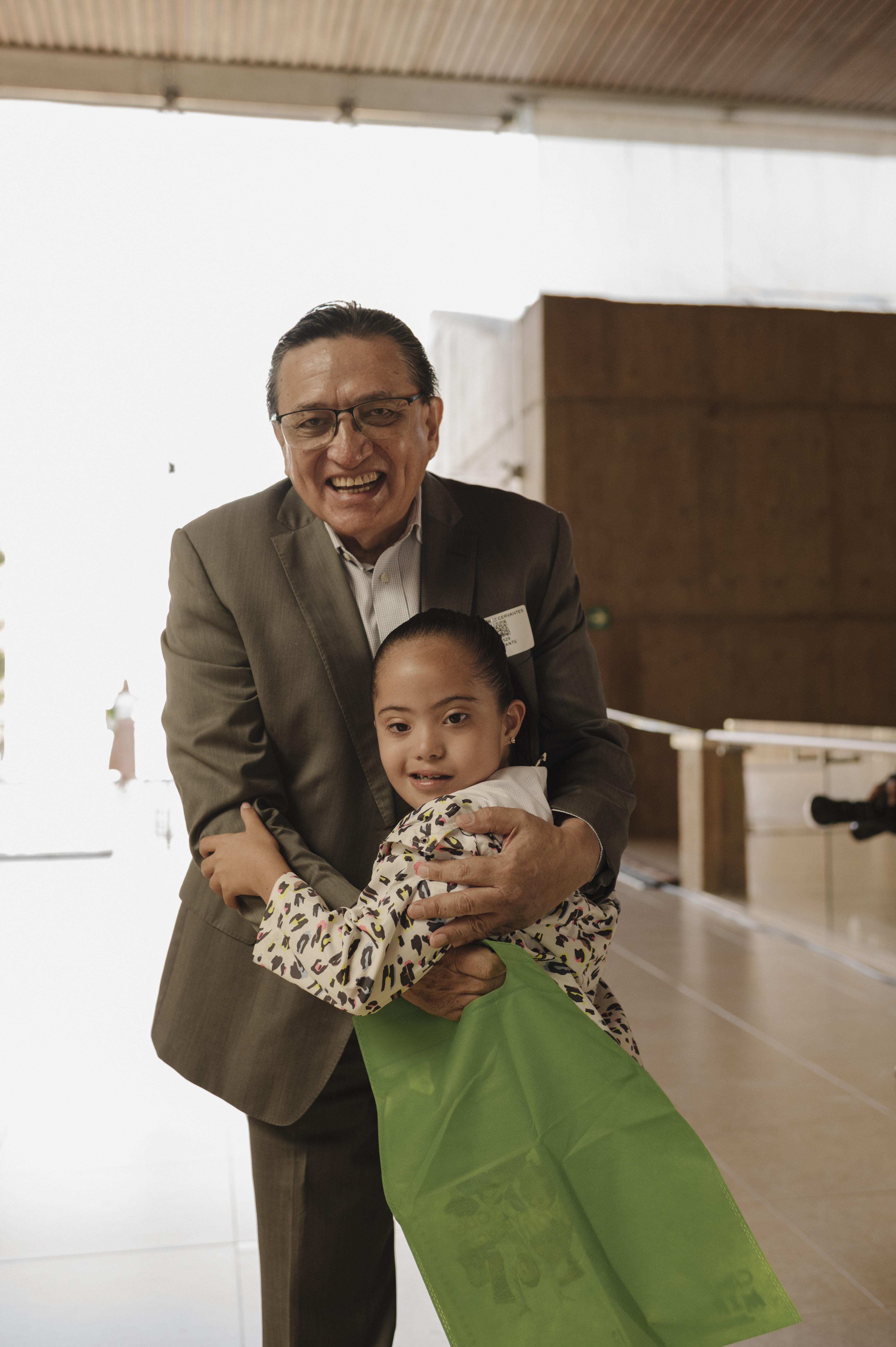 Médico sonriente con traje sosteniendo a una niña con síndrome de Down