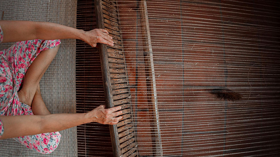 A person weaving fabric on a traditional wooden loom, showcasing intricate craftsmanship.