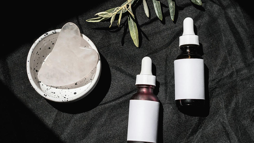 Elegant skincare product setup with gua sha tool and essential oils on a black background.