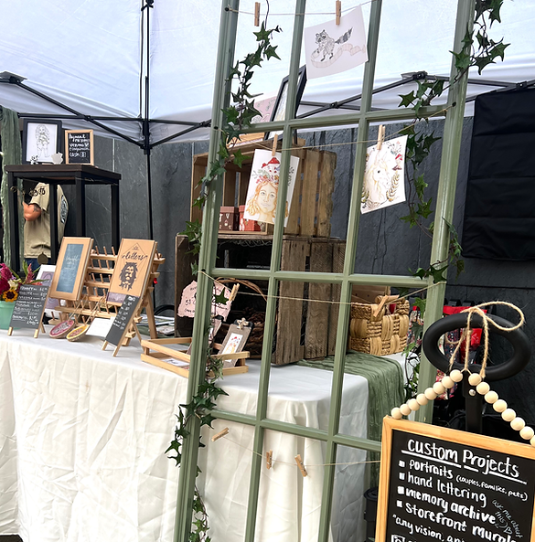 Rustic event display showing hand-made home decor, and fine art prints with wooden crates and menu board.