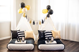 Glamorous black, gold, and white sleepover birthday party in Erie, CO, featuring striped pillows, sequin accents, and sophisticated tassel garlands on teepees.