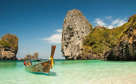 aysage côtier en Thaïlande avec un bateau traditionnel sur une eau turquoise.