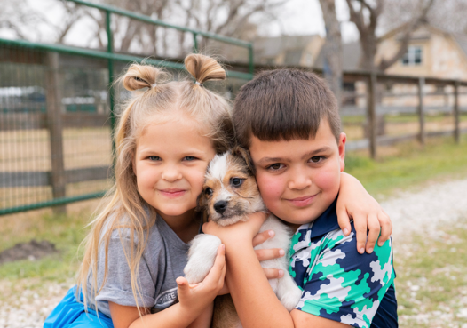 Two children holding a rescue puppy at the new property