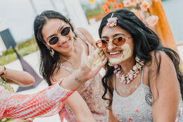 A friend applying turmeric paste to Nia's cheek during the Haldi at her Hindu wedding in Costa Mujeres