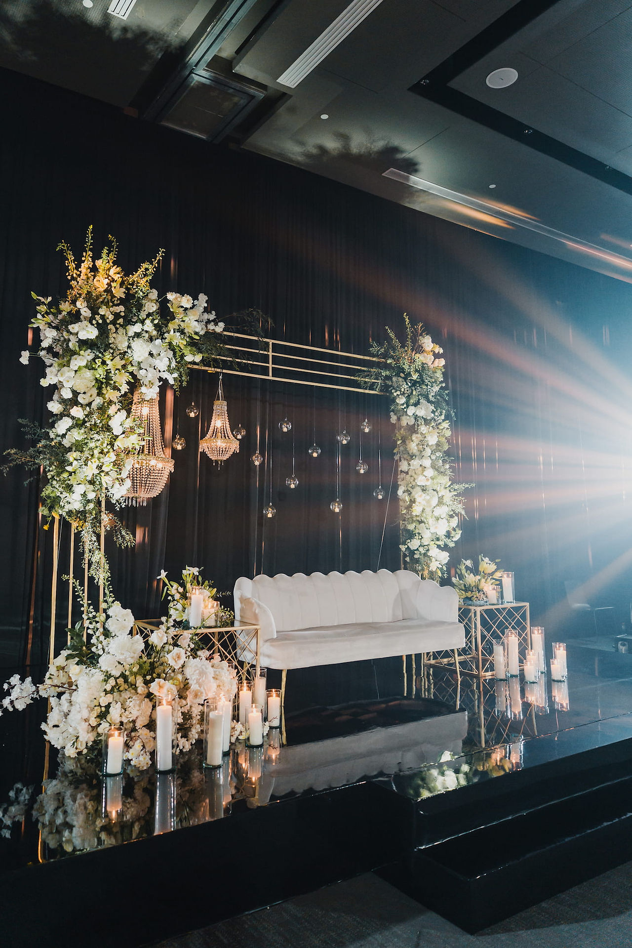 Elegant reception sweetheart stage with white floral arrangements and crystal chandeliers at Grand Palladium Costa Mujeres