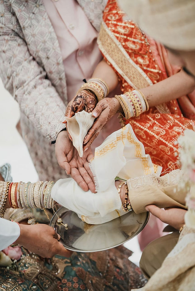 Bride and groom's hands holding a conch shell during Hindu wedding ritual at Grand Palladium Costa Mujeres