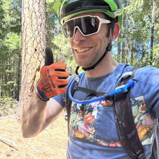 Mountain biker with orange gloves, white sunglasses and a big Ponderosa Pine in the background.