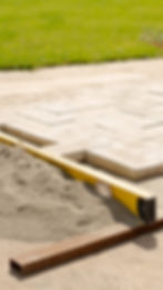 Paver patio installation in progress with level and sand base — close-up of interlocking stone pattern used in residential la