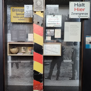 Экспонат внутри музея Трэненпаласт, показывающий знаки пограничного контроля ГДР, кусок Берлинской стены и исторические фотографии.