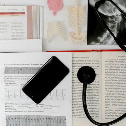 Medical textbooks, stethoscope, anatomy models, and diagnostic charts on a desk representing healthcare and medical study.