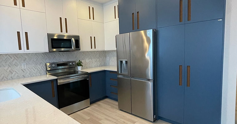 Small kitchen featuring blue and white cabinets, floating shelves, waterjet marble backsplash, and cane flush handles for a modern, airy look.