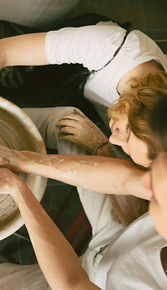 two people throwing on pottery wheel