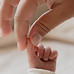 Main d'une maman qui tient le pouce de son nouveau né