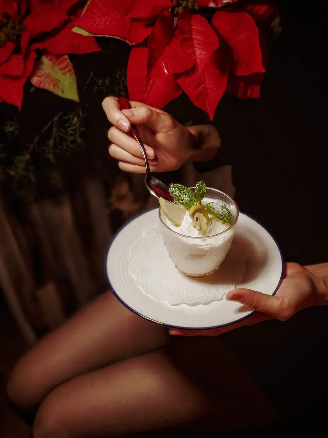 A young lady in a black dress holding a glass of Italian dessert.