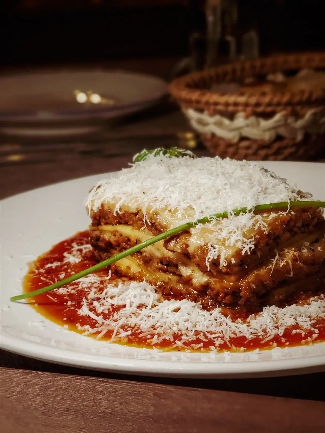 Home-made Lasagna being garnished with some parmesan cheese.