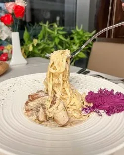 Fresh tagliatelle with porcini mushroom being lifted up by a fork.