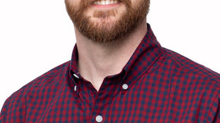 Smiling bald man with glasses and beard (Josh Murray) in a red plaid shirt against a white background