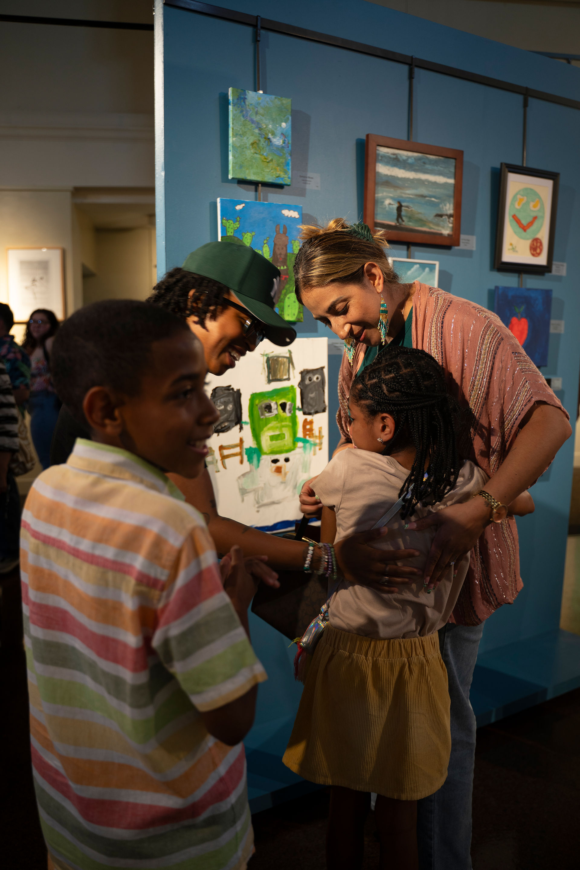 Family embraces young artist in the art gallery at the Public Works Opening Reception