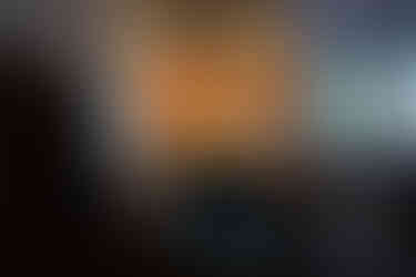 Three large oil paintings are displayed on a gallery wall; the central painting is a striking portrait of a woman with a golden halo and butterfly wings.