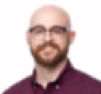 Smiling bald man with glasses and beard (Josh Murray) in a red plaid shirt against a white background