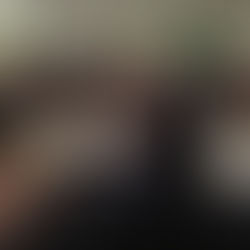 A drummer performs on stage as children sit watching in a school gym. The wall reads "Mustang Pride" with a horse mural. Mood is attentive.