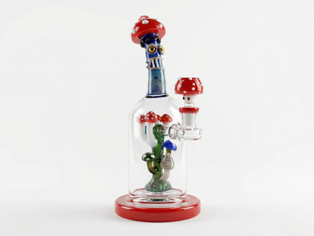 Glass bottle with colorful, mushroom-themed sculpture inside. Red and polka-dotted cap, whimsical design, on white background.