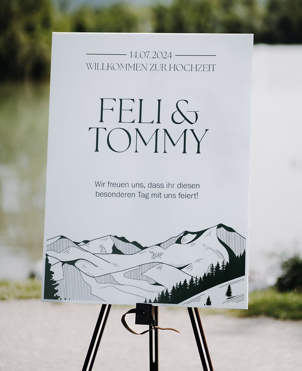 Nahaufnahme eines Willkommensschildes aus weißem Acrylglas mit einer Berglandschaft darauf