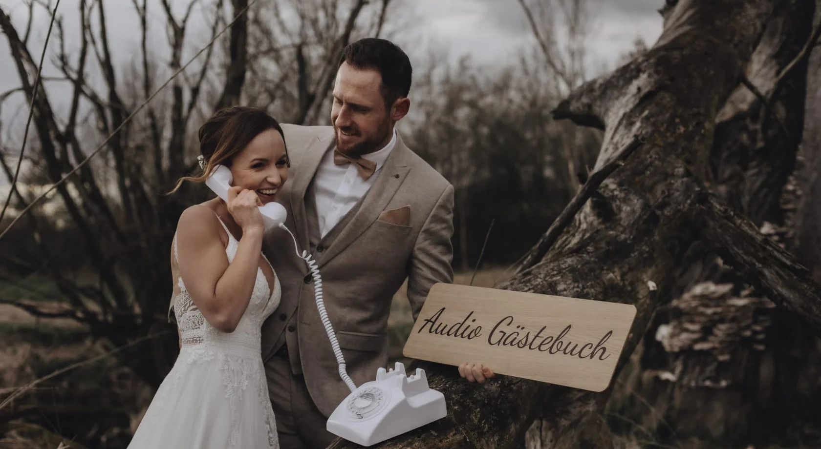 Braut und Bräutigam am weißen Telefon, Schild mit Aufschrift "Audio Gästebuch"