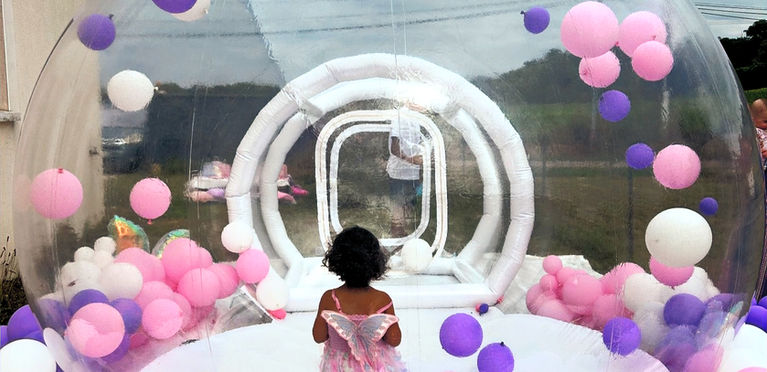 Petite fille portant une robe dans la Bubble House, ballons roses et violets.