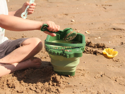 Child playing with a bucket and spade on the beach in Abergele