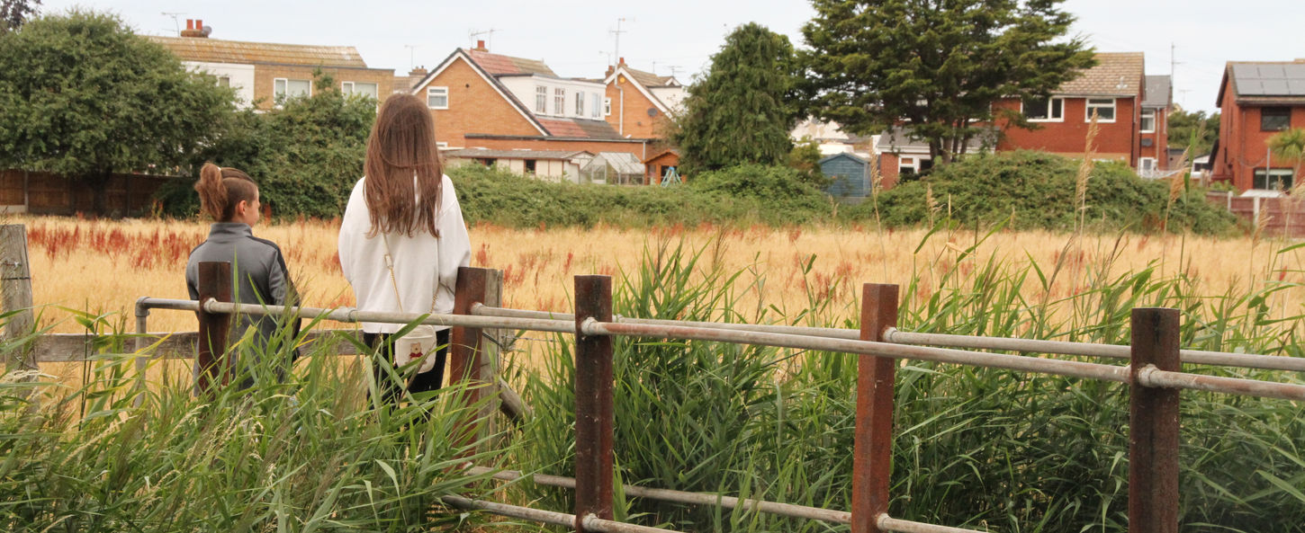 Child and teenager exploring the boardwalk and wetland habitat at Coed y Morfa.