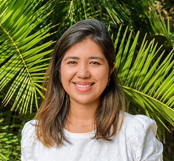 Retrato da Psicóloga Mei Goia, ao fundo folhas de palmeiras