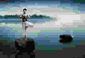 Dawn yoga, tree pose on a rock in a misty lake