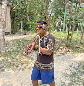 Un homme marchant en jouant de la flûte traditionnel avec un bandeau artisanal sur la tête.