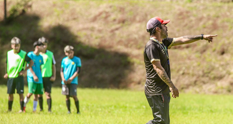 Treinador Gabriel David orientando atletas sobre posicionamento tático durante peneira de futebol.
